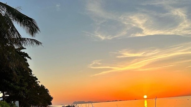 A beach with a sunset, calm water, and boats. - MAI Place by Aforetime (Koh Samui)