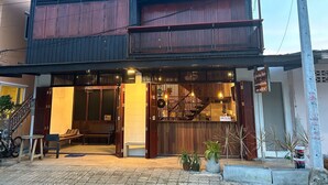 A two-story building with a wooden facade, a staircase leading to the upper floor, and a small outdoor seating area with a bench and table. - MAI Place by Aforetime (Koh Samui)