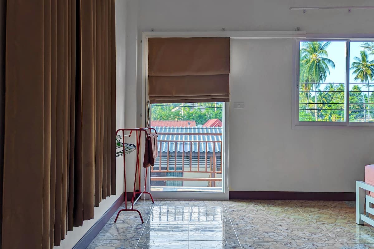 A room with a large window, a metal rack with a towel, and a tiled floor.