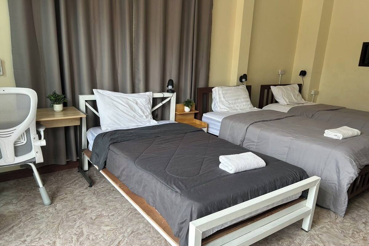 A hotel room with two beds, a desk, and a chair.