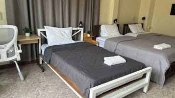 A hotel room with two beds, a desk, and a chair.