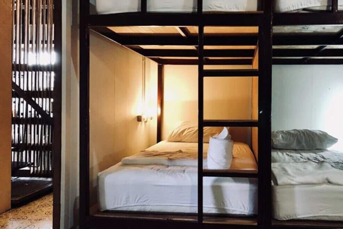 A bunk bed room with a wooden frame, a bedside table, and a lamp.