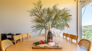 Een eettafel met een fles Piper Heidsieck champagne, glazen, crackers en een decoratieve plant.