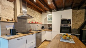 Een moderne keuken met witte kastjes, houten aanrecht en een roestvrijstalen afzuigkap, plus een inbouwoven.