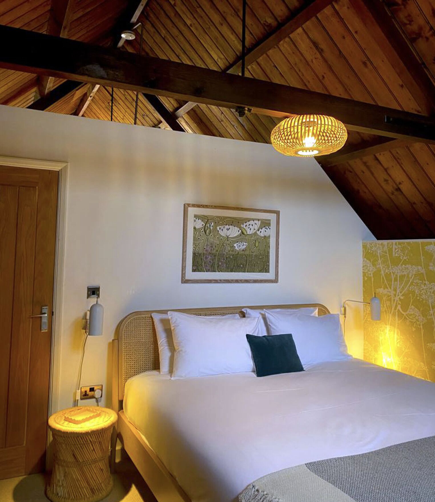 Une chambre à coucher avec un lit, une lampe de chevet, un tableau encadré au mur et un plafond en bois.