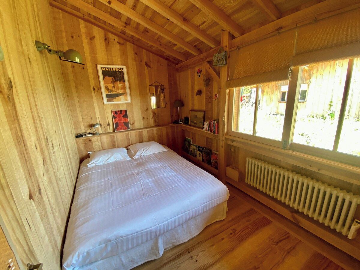 Une pièce en bois avec un lit, un radiateur et une fenêtre.
