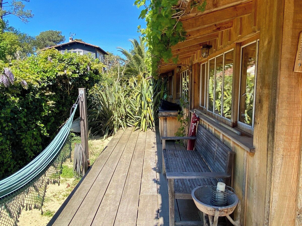 A wooden deck with a hammock, a bench, and a small table.