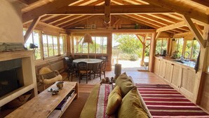 L’intérieur d’un chalet en bois chaleureux et accueillant, avec un coin repas, un canapé et une cheminée.