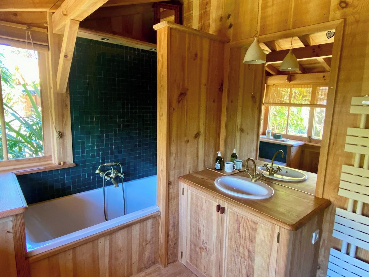 A wooden bathroom with a bathtub, a sink, and a window.