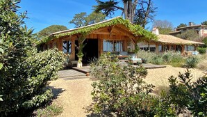 Une maison en bois à l’allure rustique, dotée d’un porche abrité et d’un chemin de terre menant à l’entrée.