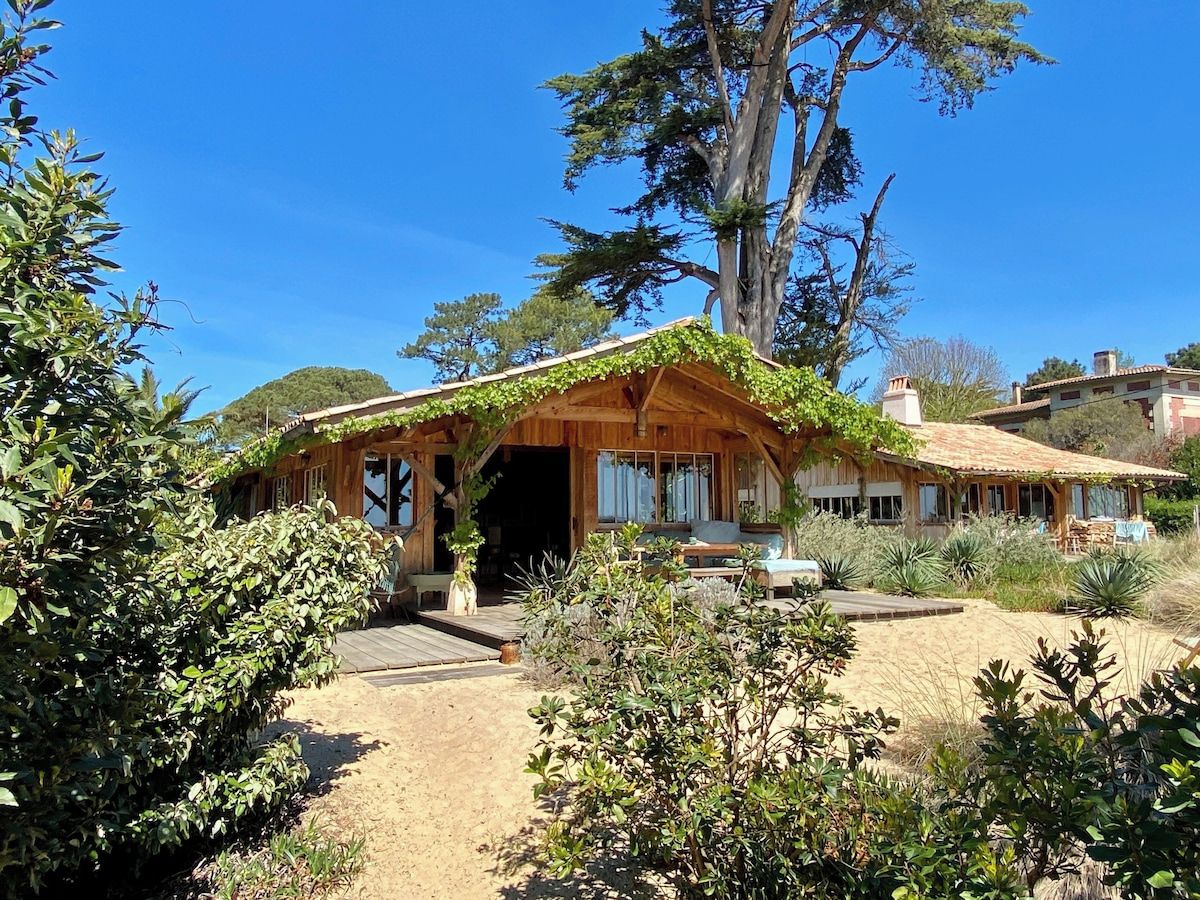 Eine Holzhütte mit Veranda, umgeben von viel Grün und blauem Himmel.