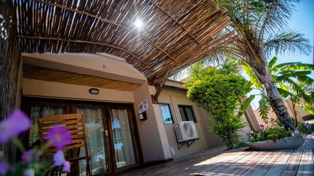 A covered outdoor area with a wooden bench, a potted plant, and a building with a number '8' sign.