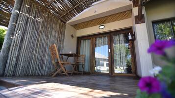 Un patio cubierto con una mesa y sillas de madera, un letrero con el número 8, y vistas a través de puertas de vidrio.