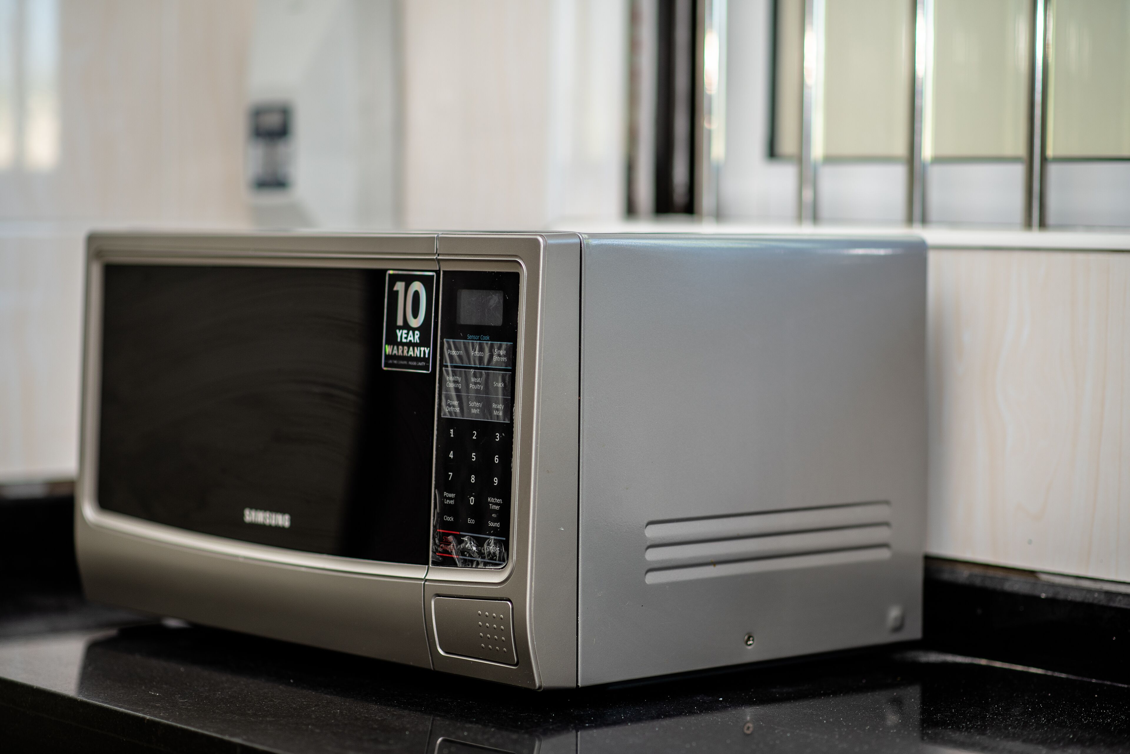 A microwave oven with a 10-year warranty sticker on the control panel.