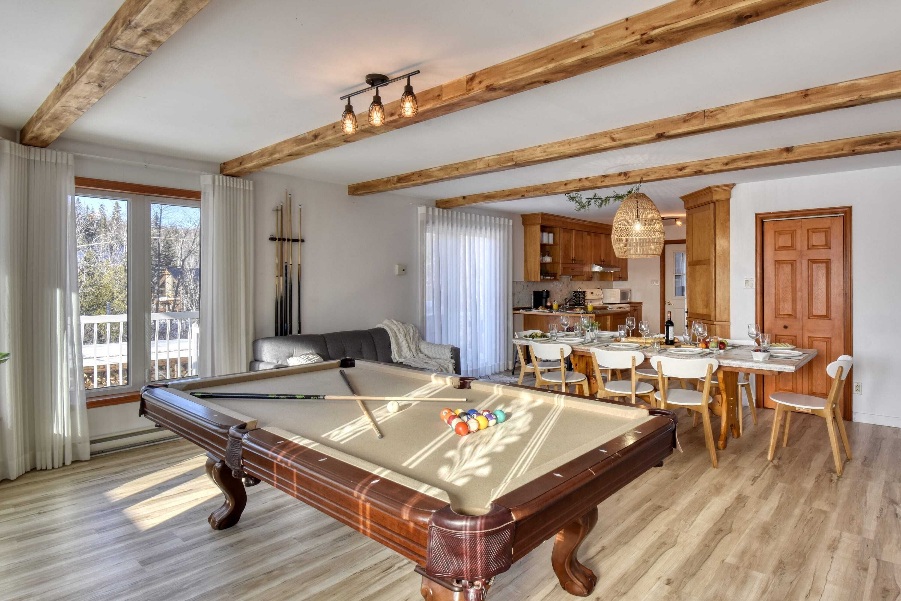 Amplia habitación con mesa de billar, vigas de madera, comedor y cocina.