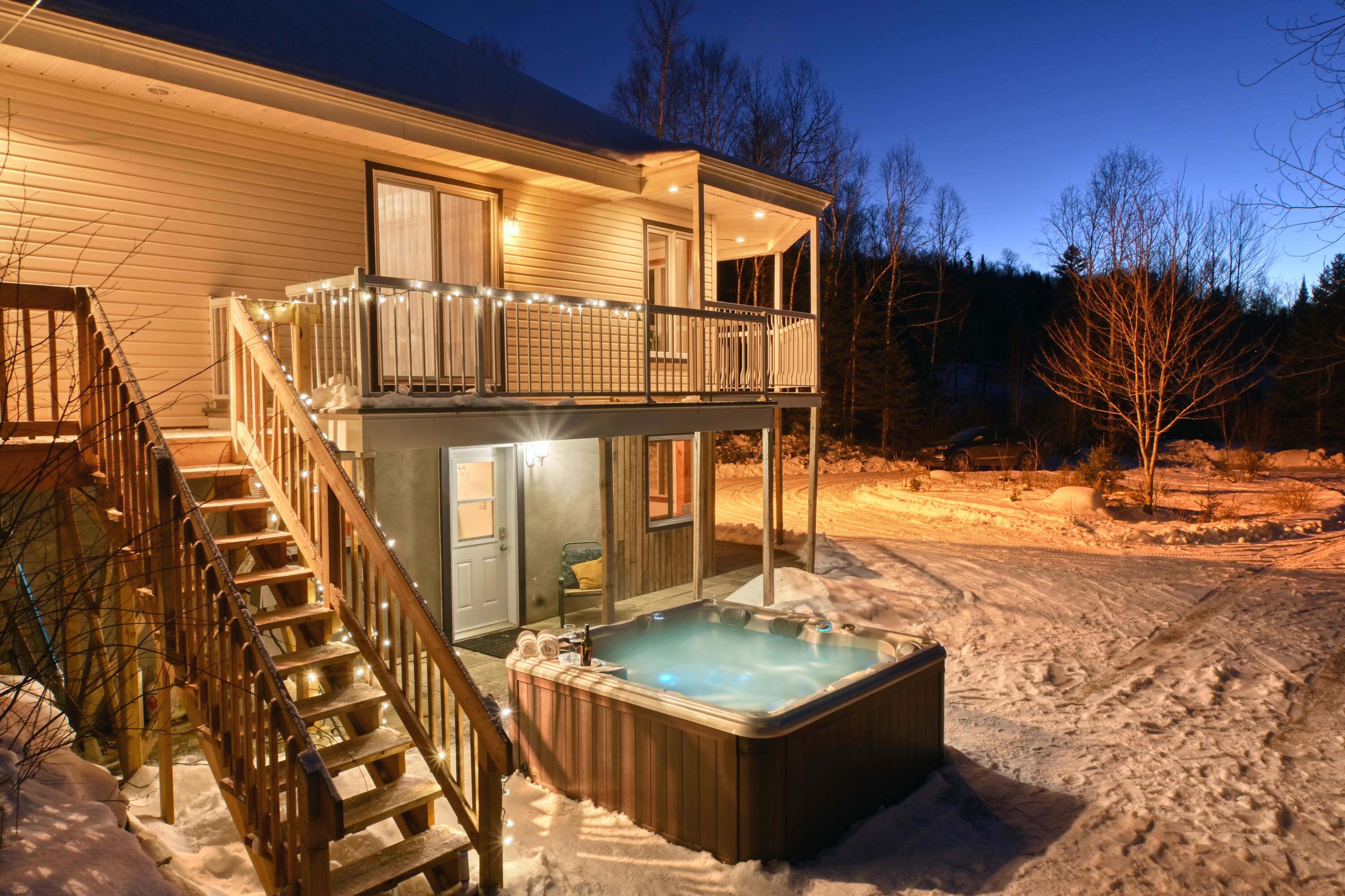 Een huis met twee verdiepingen, met een jacuzzi op de begane grond en een balkon met lichtjes.