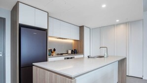 A modern kitchen with a central island, built-in appliances, and a minimalist design. - Luxury Signature Stay Ocean Views 2BR Lvl 9 (Broadbeach)