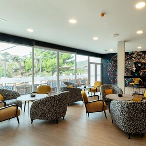 A modern interior with patterned seating, large windows, and a mural. - Hotel Altos de Istán (Istan)