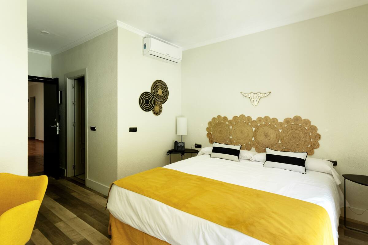 A hotel room with a bed, a bedside table, a chair, and a door.
