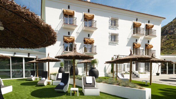 A hotel with outdoor lounge areas, white walls, and thatched umbrellas. - Hotel Altos de Istán (Istan)