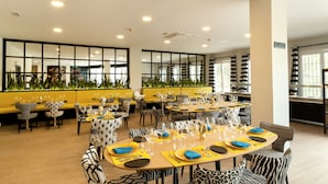 A modern dining area with multiple tables and chairs, featuring a yellow and black color scheme. - Hotel Altos de Istán (Istan)