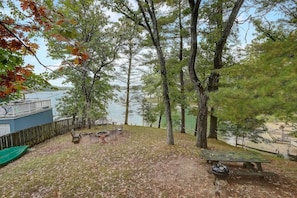 A lakeside outdoor area with picnic tables, a barbecue grill, and a view of the lake. - Pine Bay Lodge - Lakefront (Wisconsin Dells)