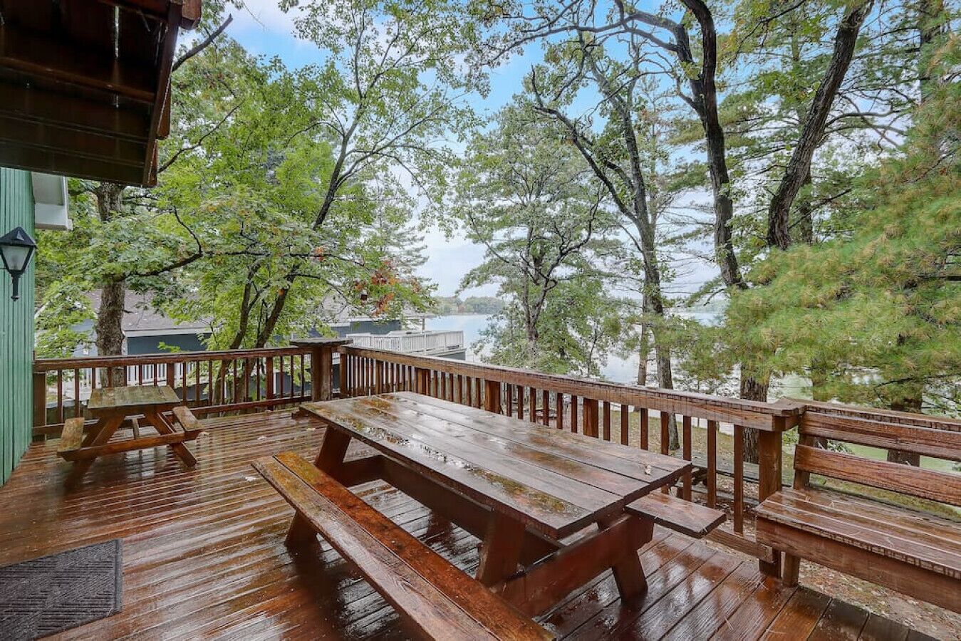 Une terrasse en bois avec des tables de pique-nique et des bancs, donnant sur une étendue d’eau.