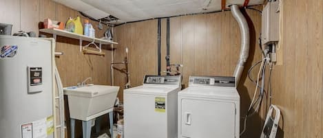 Un cuarto de lavandería con un lavamanos, dos lavadoras y un refrigerador.