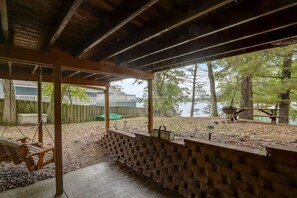 A covered patio with a swing set, a brick wall, and a view of a lake.