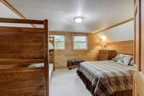 A bedroom with a bunk bed, a single bed, a dresser, and a window.