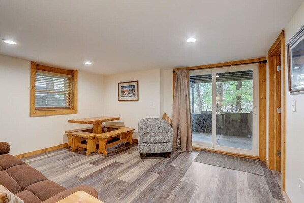A cozy living room with a wooden dining table, a patterned armchair, and a brown sofa. - Pine Bay Lodge - Lakefront (Wisconsin Dells)