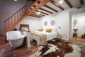 A bedroom with a wooden staircase, a white bathtub, a bed with white bedding and a cowhide rug. - Marias Guesthouse beja (Beja)