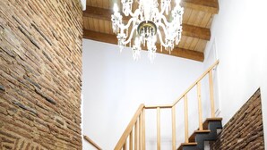 A staircase with wooden railings and a chandelier, leading to a white door. - Marias Guesthouse beja (Beja)