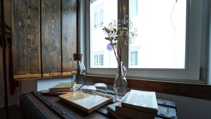 A wooden table with books, a glass vase with flowers, and a cork bottle. - Marias Guesthouse beja (Beja)