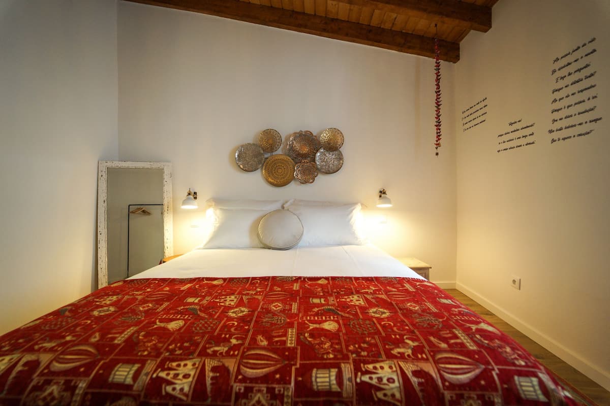 A hotel room with a large bed, a decorative wall hanging, and a small bedside table.