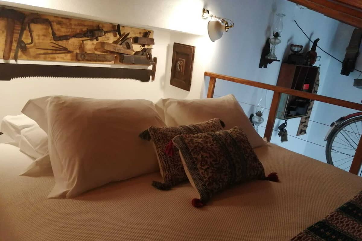 A bed with two pillows, a headboard, and a wall-mounted light fixture.
