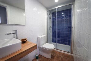 A bathroom with a white sink, a toilet, and a shower with blue tiles. - Marias Guesthouse beja (Beja)