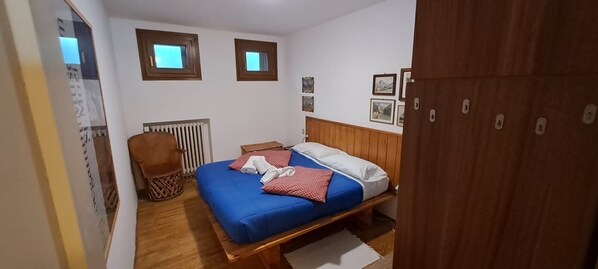 Une chambre à coucher avec un lit, une chaise, un radiateur et une armoire en bois.