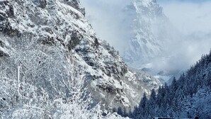 A snow-covered mountain landscape with a building featuring a sloped roof and multiple windows. - Appartamento Cervinia Fronte Funivie (CERVINIA)