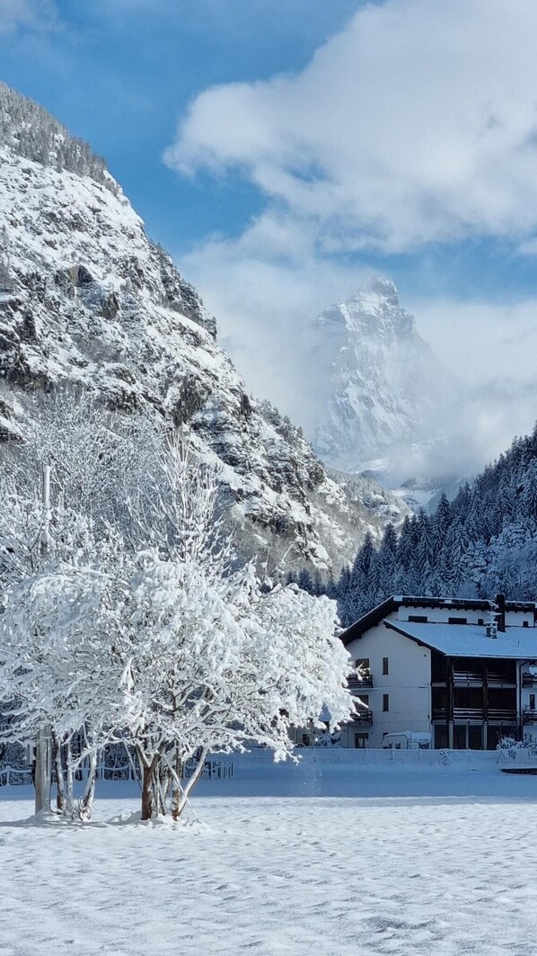 Un paisaje montañoso cubierto de nieve, con un edificio de techo inclinado y varias ventanas.
