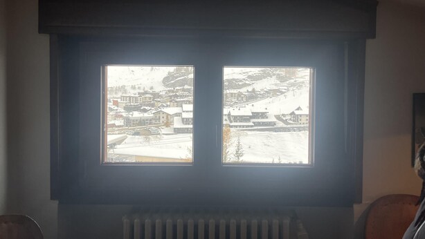 A window with a view of a snowy town and a mountain. - Appartamento Cervinia Fronte Funivie (CERVINIA)
