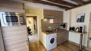 Een moderne keuken met houten kasten, een ingebouwde wasmachine, een magnetron en een koffiezetapparaat.