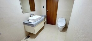 Une petite salle de bain avec un lavabo blanc, un miroir et des toilettes.