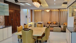 Una sala de estar moderna con comedor, que incluye una araña, un conjunto de sofás y una gran mesa de comedor con sillas.