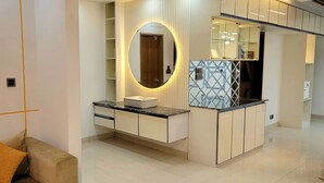 Un baño moderno con tocador, un espejo grande y una estantería empotrada.