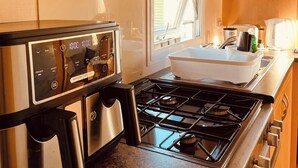 A compact kitchen with a gas stove, a built-in oven, and a window providing natural light. - Newton Stewart-sleeps 6-pool-parking-pet Friendly (Newton Stewart)