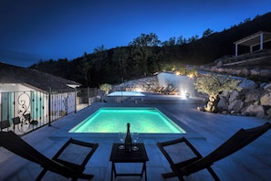 A pool area with lounge chairs and a table with a bottle and glasses. - Villa Lapis With Private Pool (Buzet)