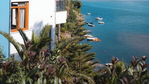 A modern building with balconies overlooking a calm sea with boats.