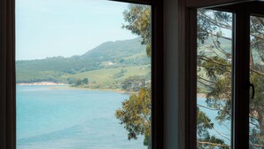 A room with a large window overlooking a body of water and hills.