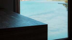 A room with a large window overlooking a body of water and hills.